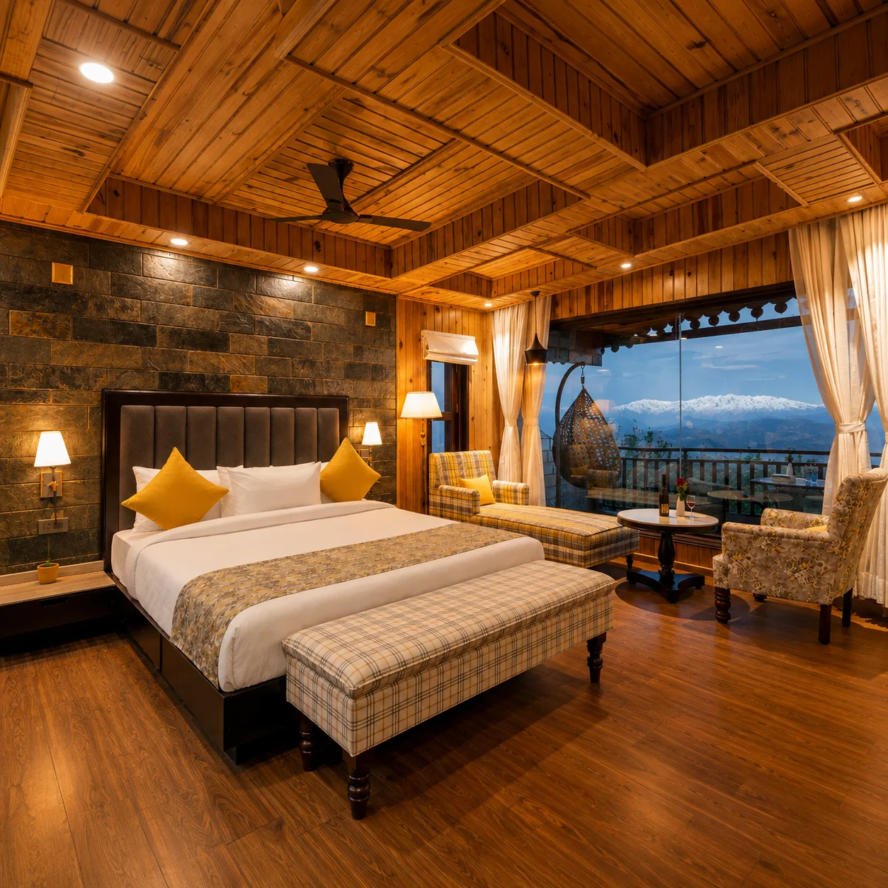 Wood-paneled suite with a stone accent wall, plaid seating, and a window view of snow-capped peaks at dusk.