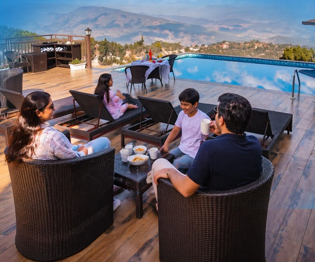 Family enjoying refreshments beside a scenic resort infinity pool with mountain views