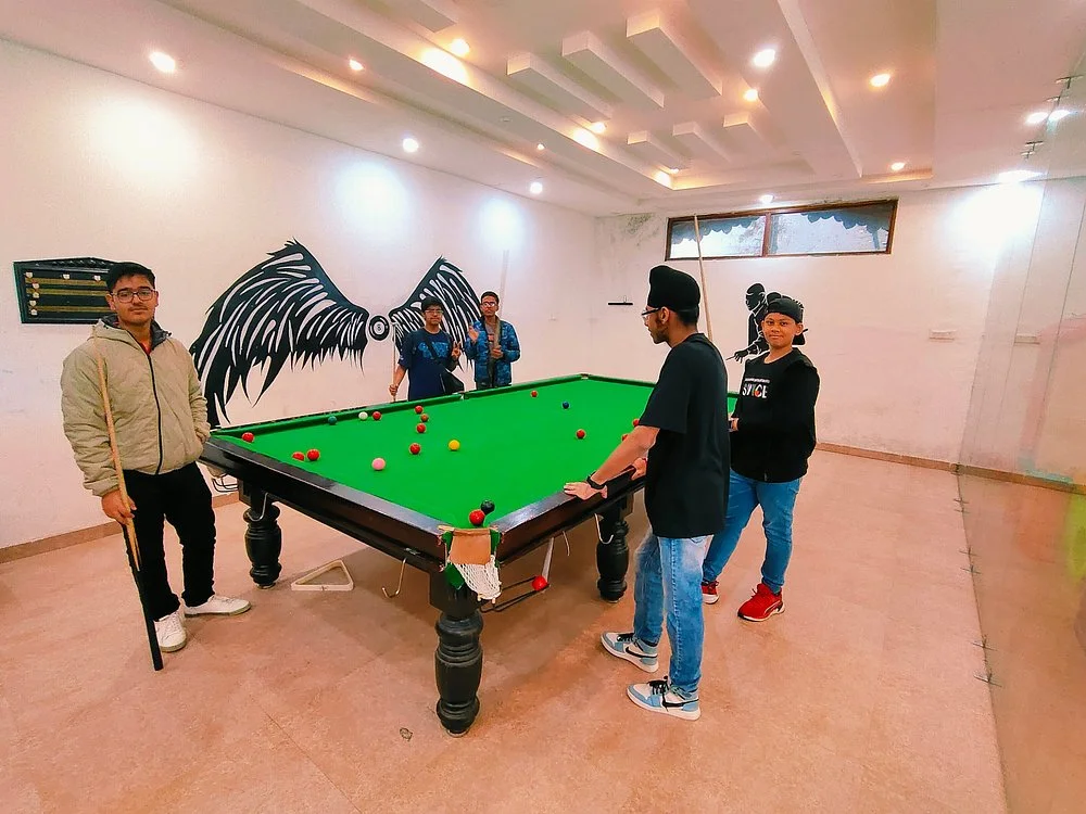 Friends playing snooker at a luxury resort indoor games room with a billiards table.