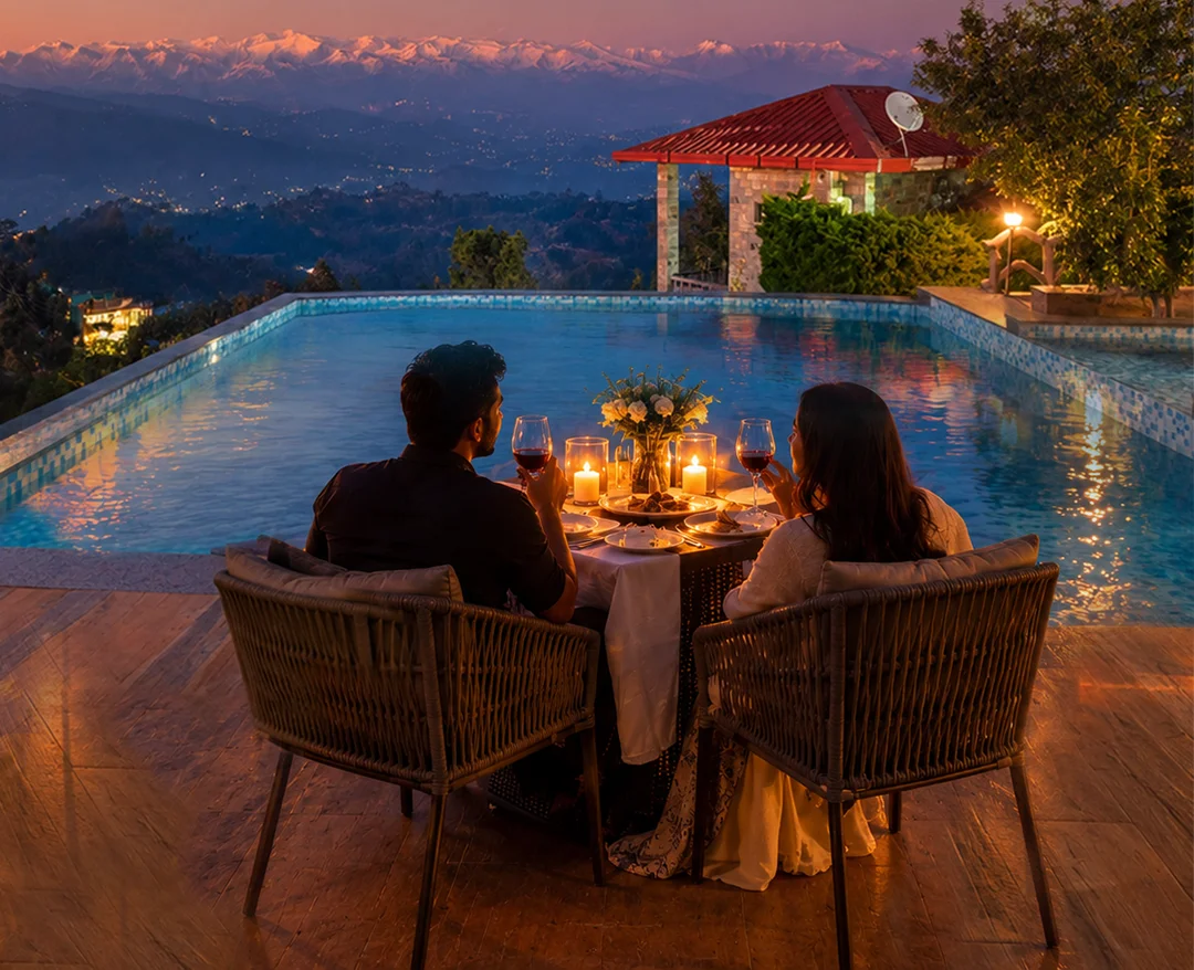Couple enjoying a candlelit dinner beside a resort pool with Himalayan mountain views