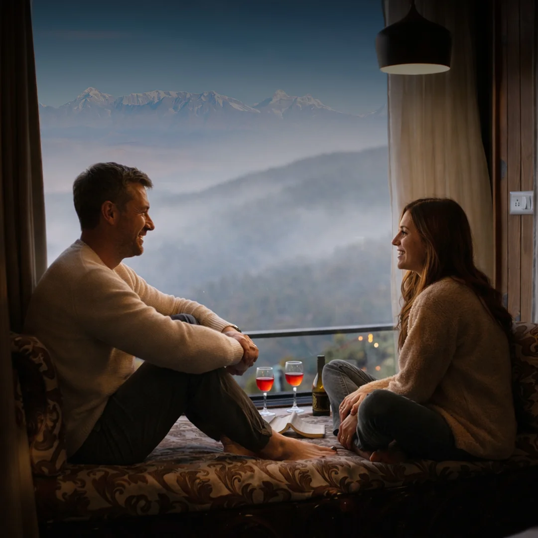 Couple relaxing on window seat with wine, enjoying mountain view at dusk