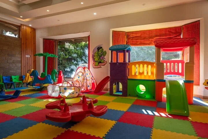 A colorful indoor play area for young children, equipped with safe toys, slides, and soft mats.