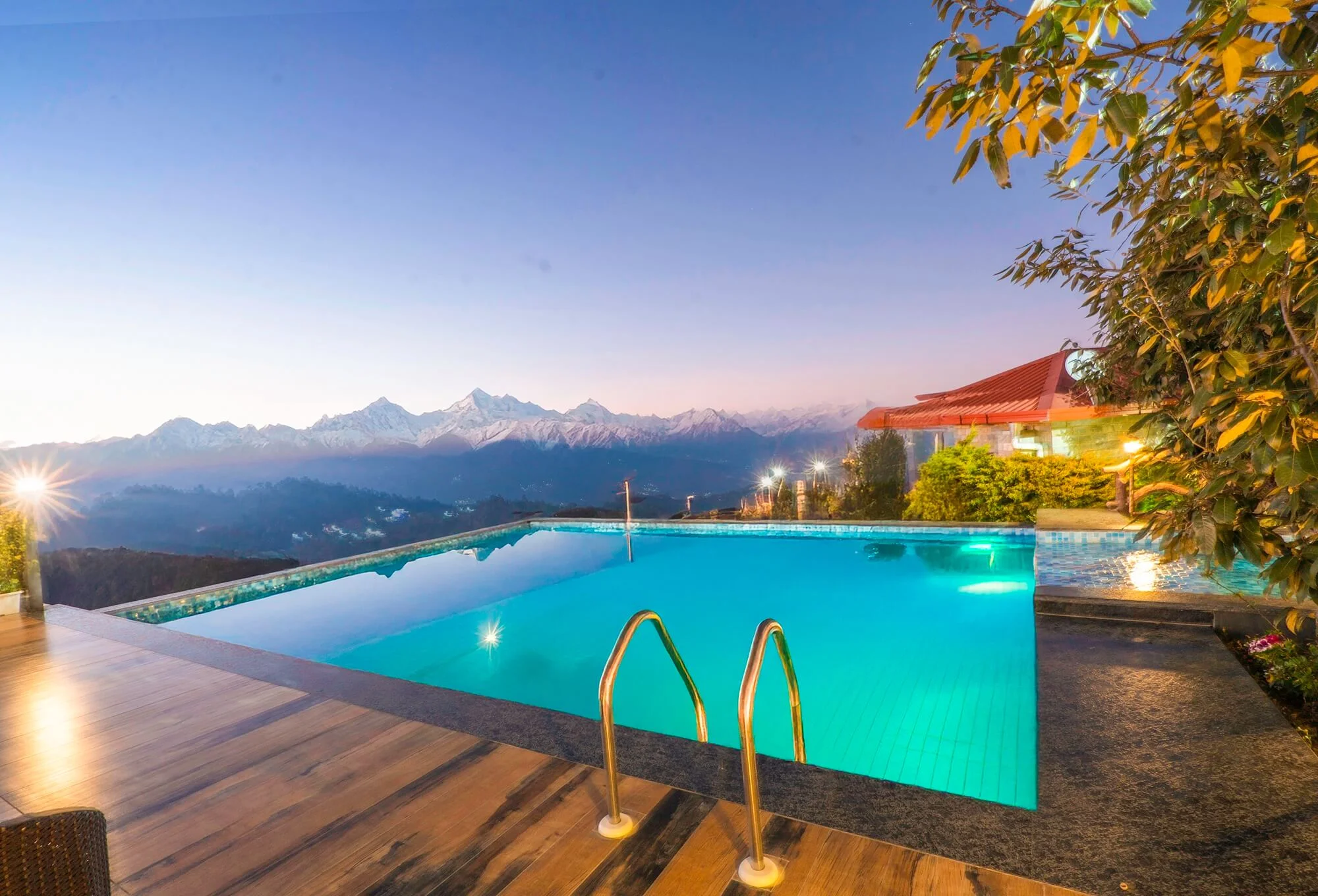 A guest relaxing at the edge of the infinity pool at Ojaswi Resort, taking in the expansive mountain landscape.